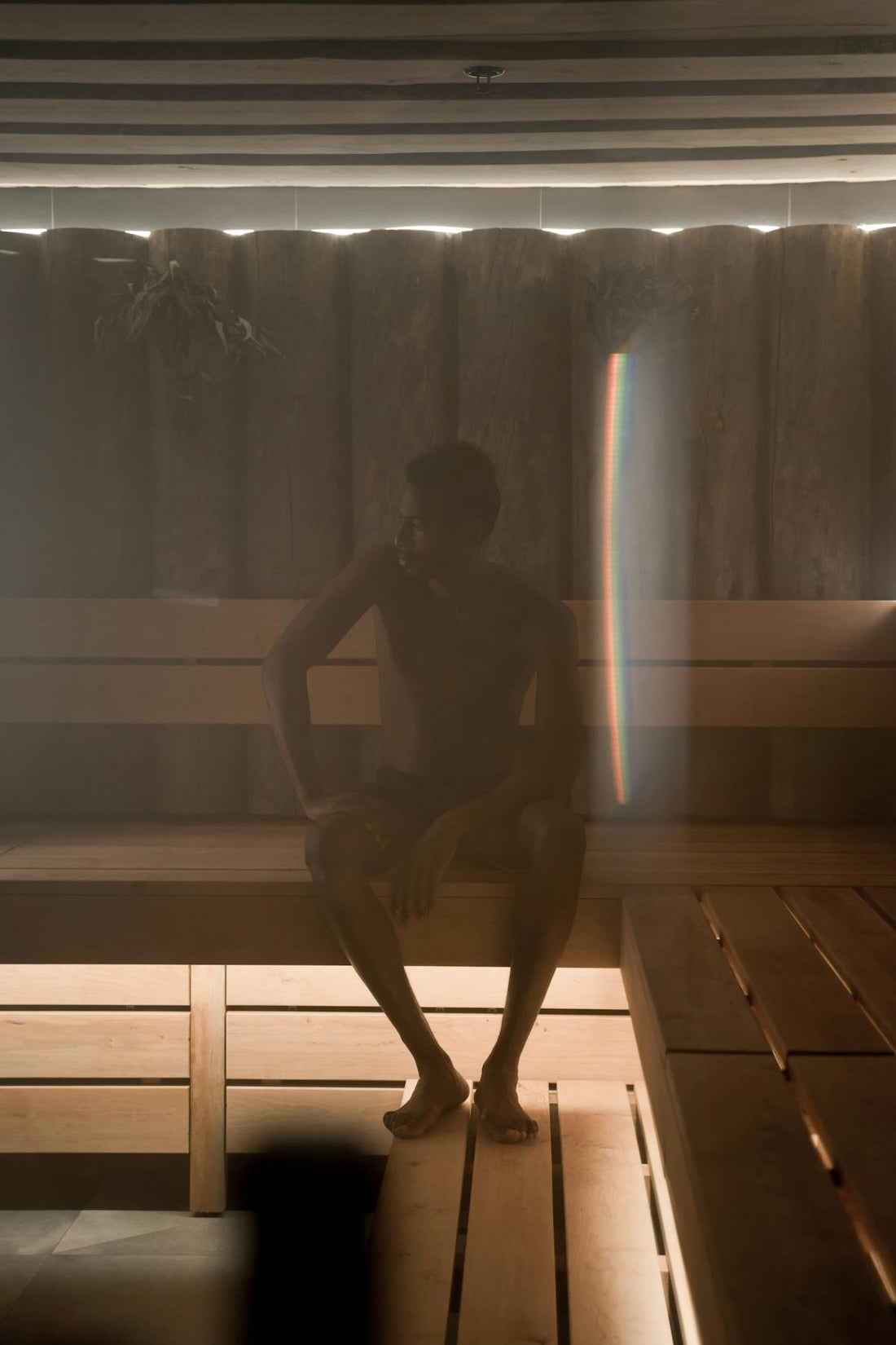 Person inside a wooden sauna room representing wellness recovery modalities